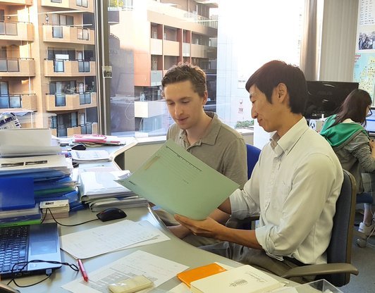 Innovative Languageのオフィスで資料を見ながら打ち合わせするインターンと社員
